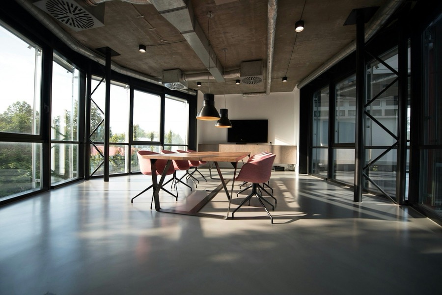 A finished office interior with steel-framed glazing, a timber meeting table and sunlight across the floor