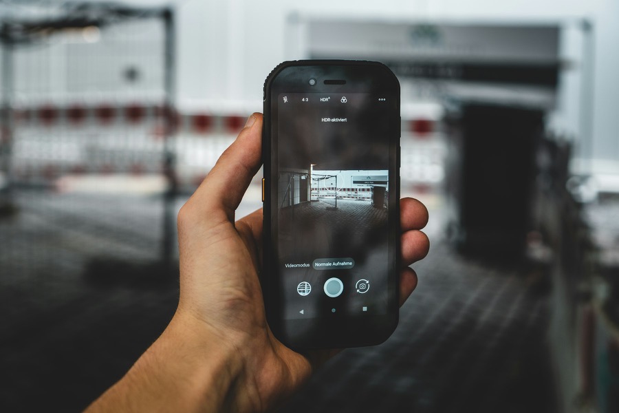 A hand holding a phone in camera mode, photographing the inside of a building site