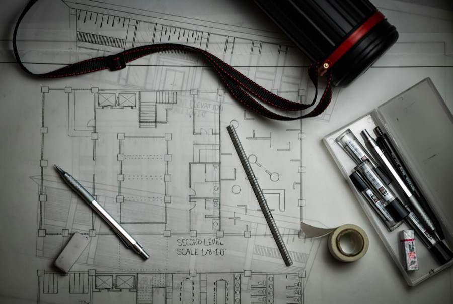 Architectural floor plans on a table with a scale ruler and a pencil