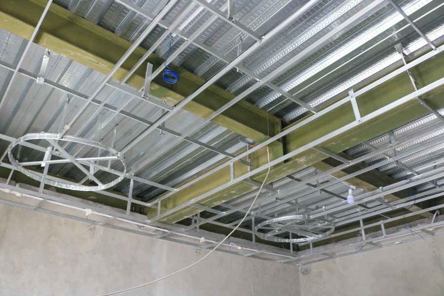 A suspended ceiling grid partway through installation under a steel deck
